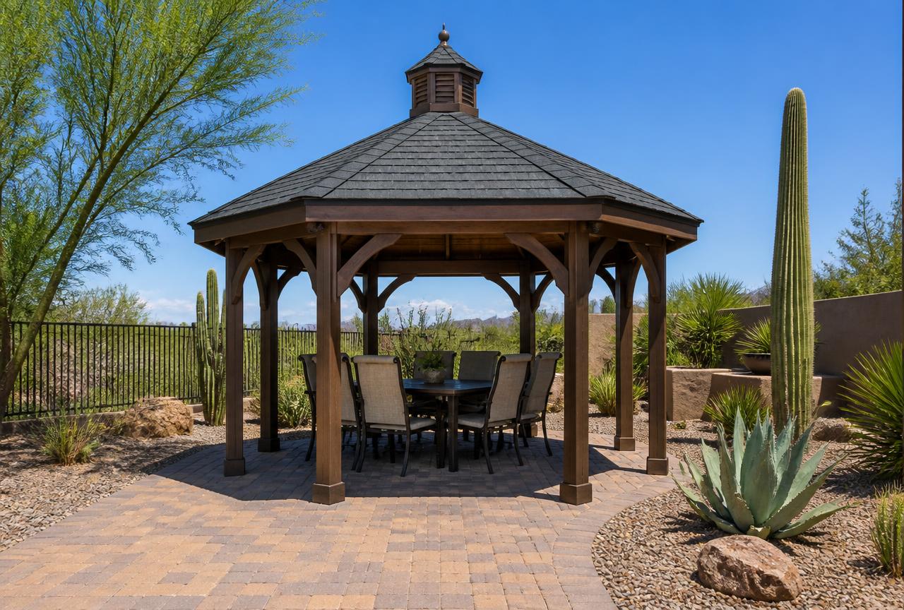 Hexagonal wood gazebo with a solid shingled roof and cupola on a paver patio in an Arizona desert backyard