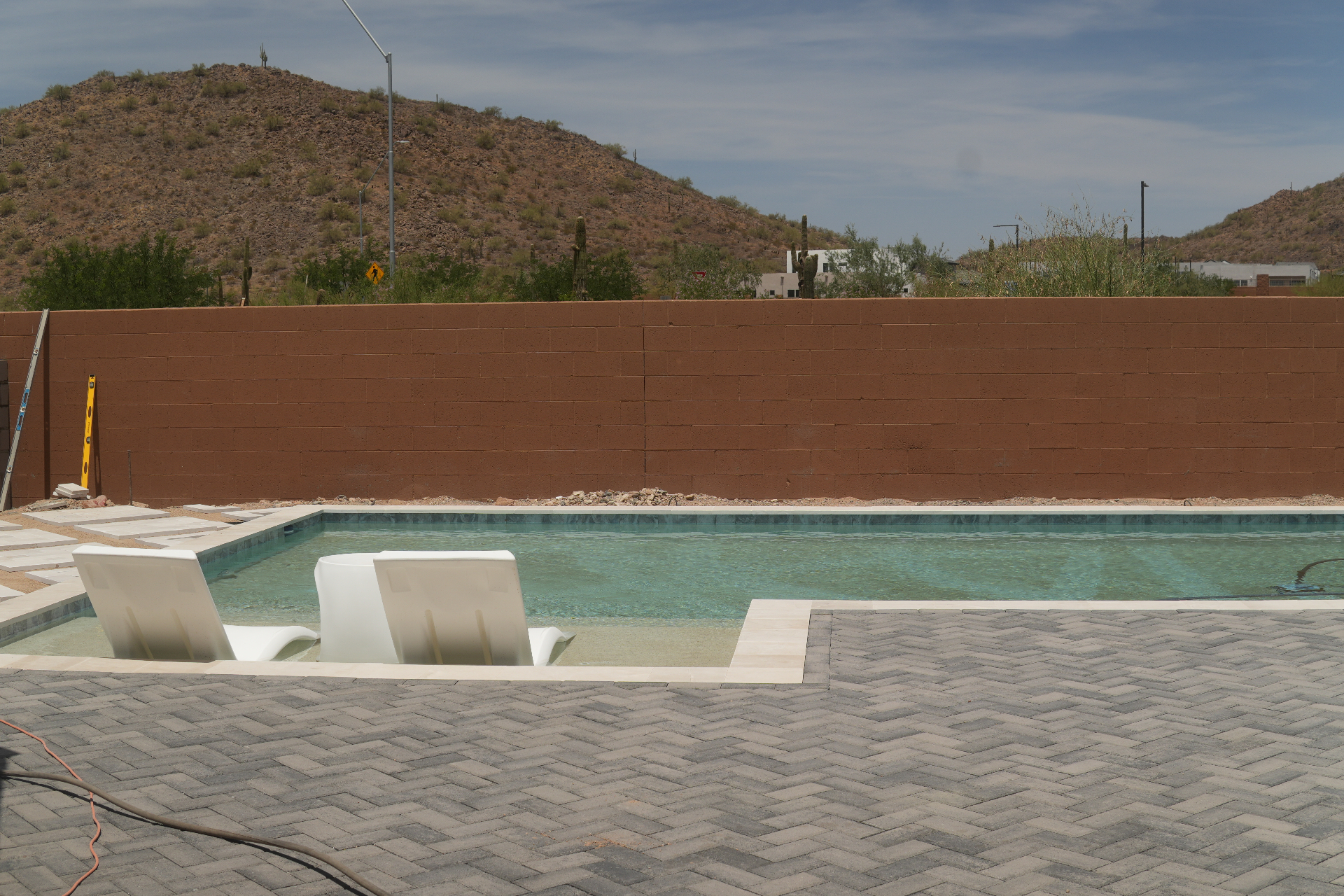 Large Baja shelf tanning ledge in an Arizona pool with umbrella sleeves and lounge chairs in shallow water
